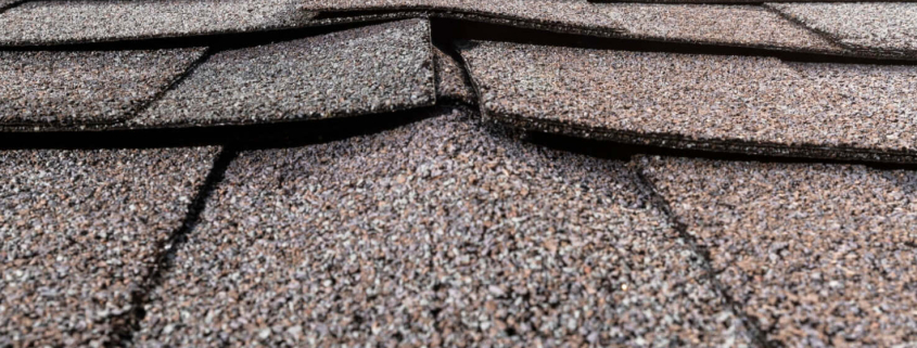 A photo showing various types of buckled shingles on a roof