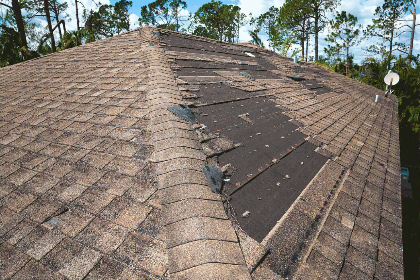 A roof with several missing shingles, indicating potential wind damage