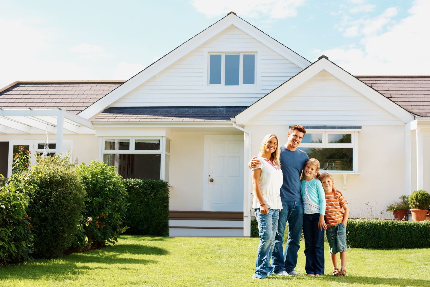 A Happy Family Poses Together In Front Of Their Home With A New Roof.