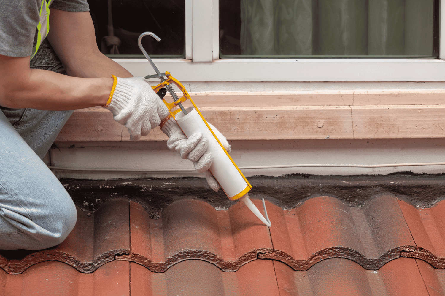 Applying roofing cement to fix a minor roof leak.